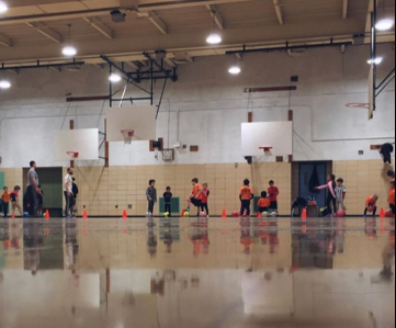 A group of people standing in the middle of an indoor gym.